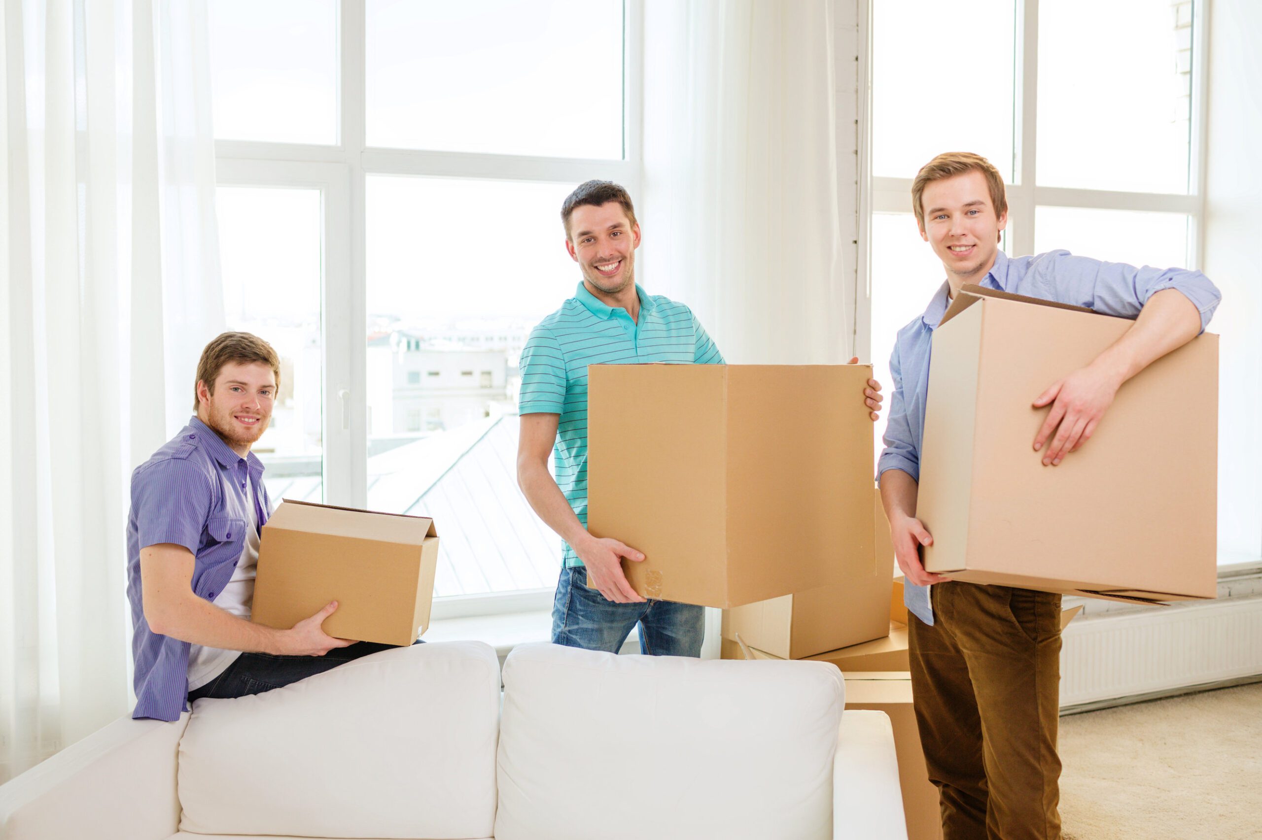moving, real estate and friendship concept - smiling male friends carrying boxes at new place